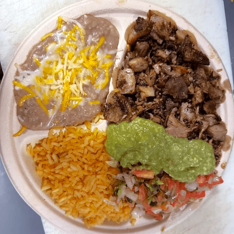 A Mexican plate with refried beans, rice, carnitas, guacamole, and pico de gallo.