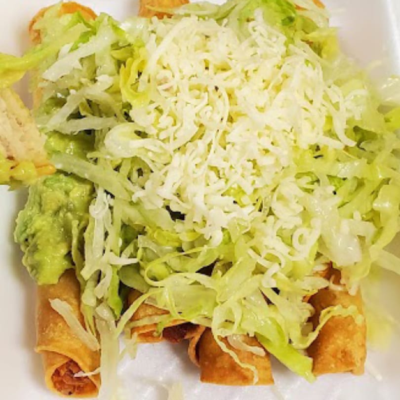 Eduardos Taco Shop's taquitos topped with shredded lettuce, cheese, and a dollop of guacamole.